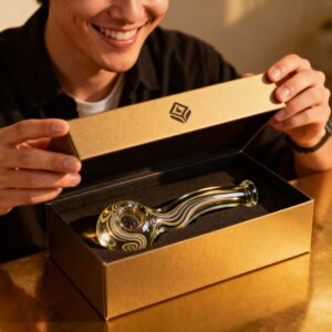 Amber tinted glass hand pipe with white gray swirls presented in a gold unboxing box