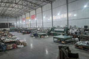 Glass pipe factory workshop with green machinery, wooden workbenches and production tools for OEM manufacturing