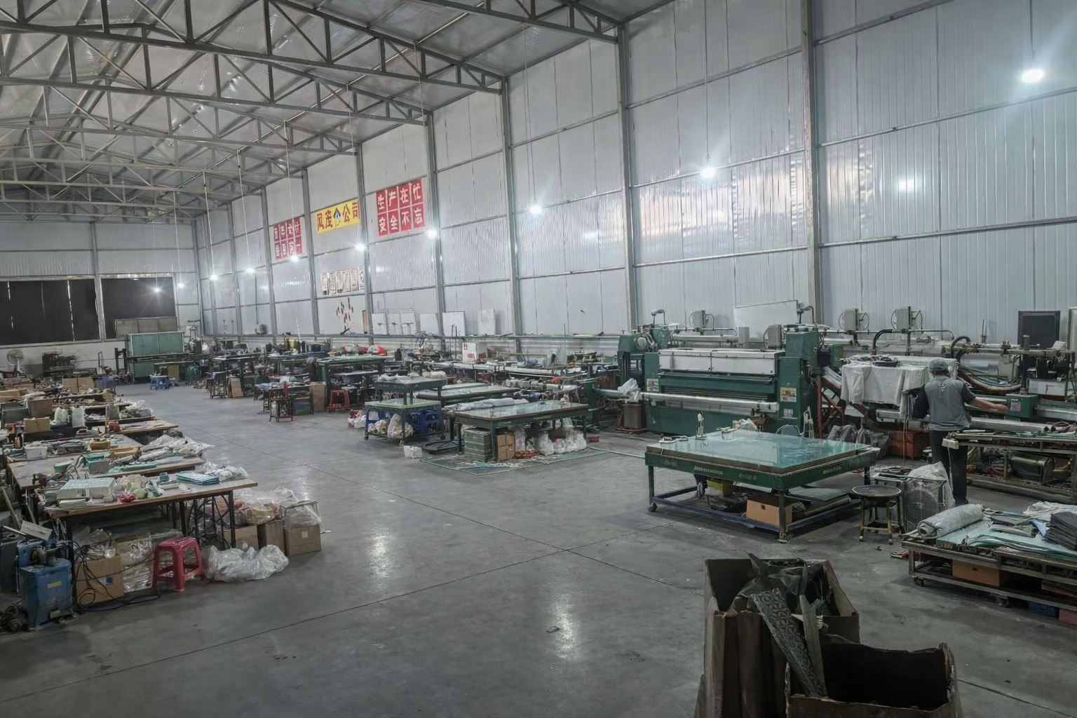 Glass pipe factory workshop with green machinery, wooden workbenches and production tools for OEM manufacturing