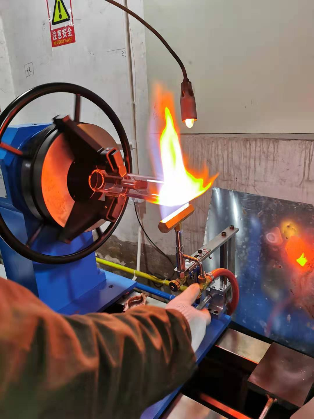 Glassblower shaping straight tube water pipe during manufacturing process