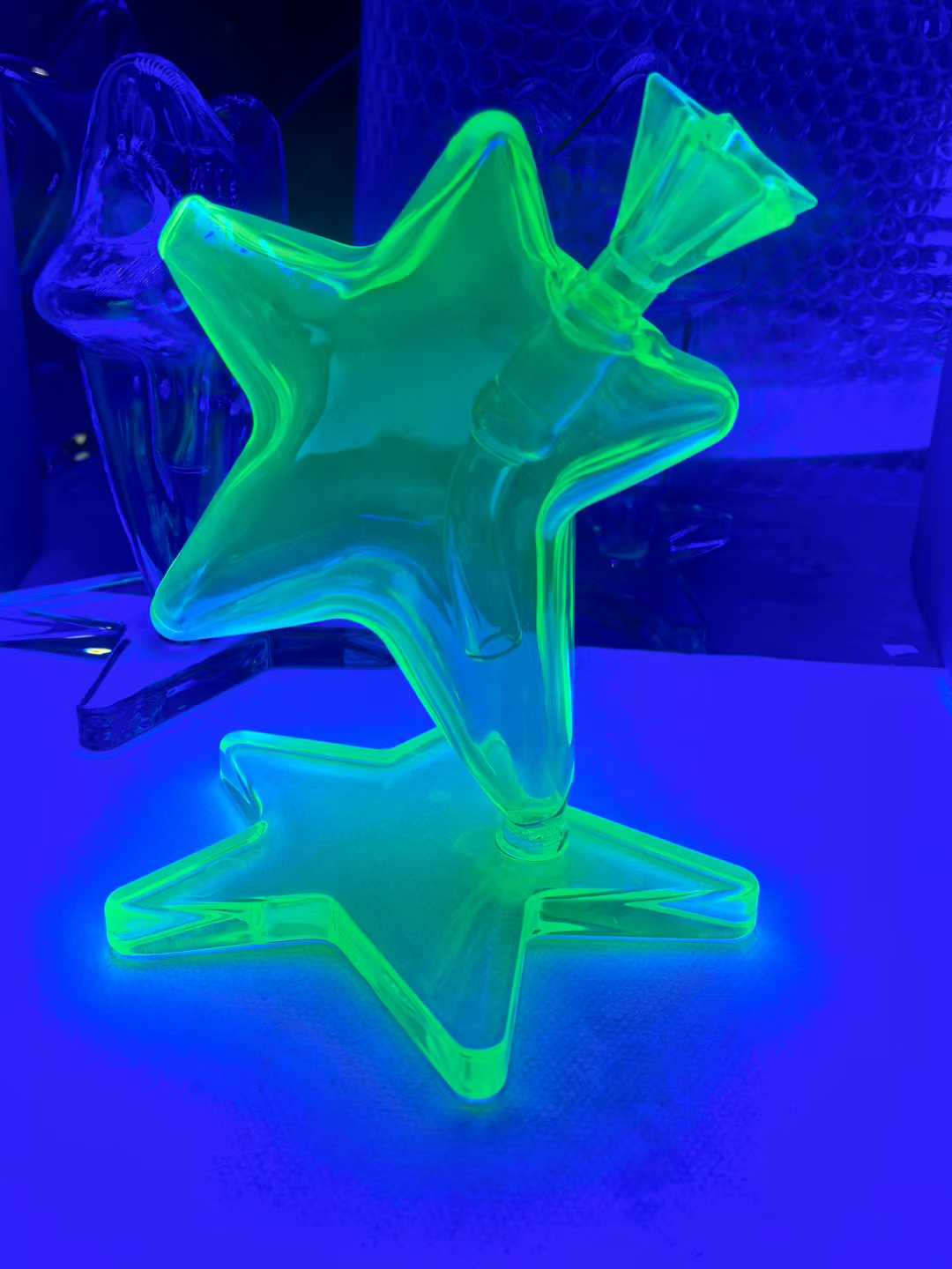 Star-shaped glass bong glowing green under UV light